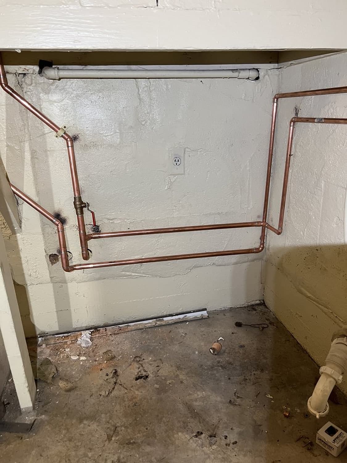 New copper water lines run along a white wall to the laundry and sink hookups