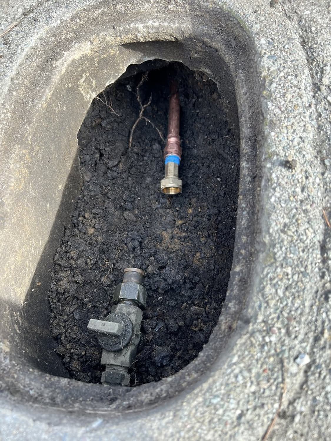 A new main line connection and valve inside an open meter box in the ground