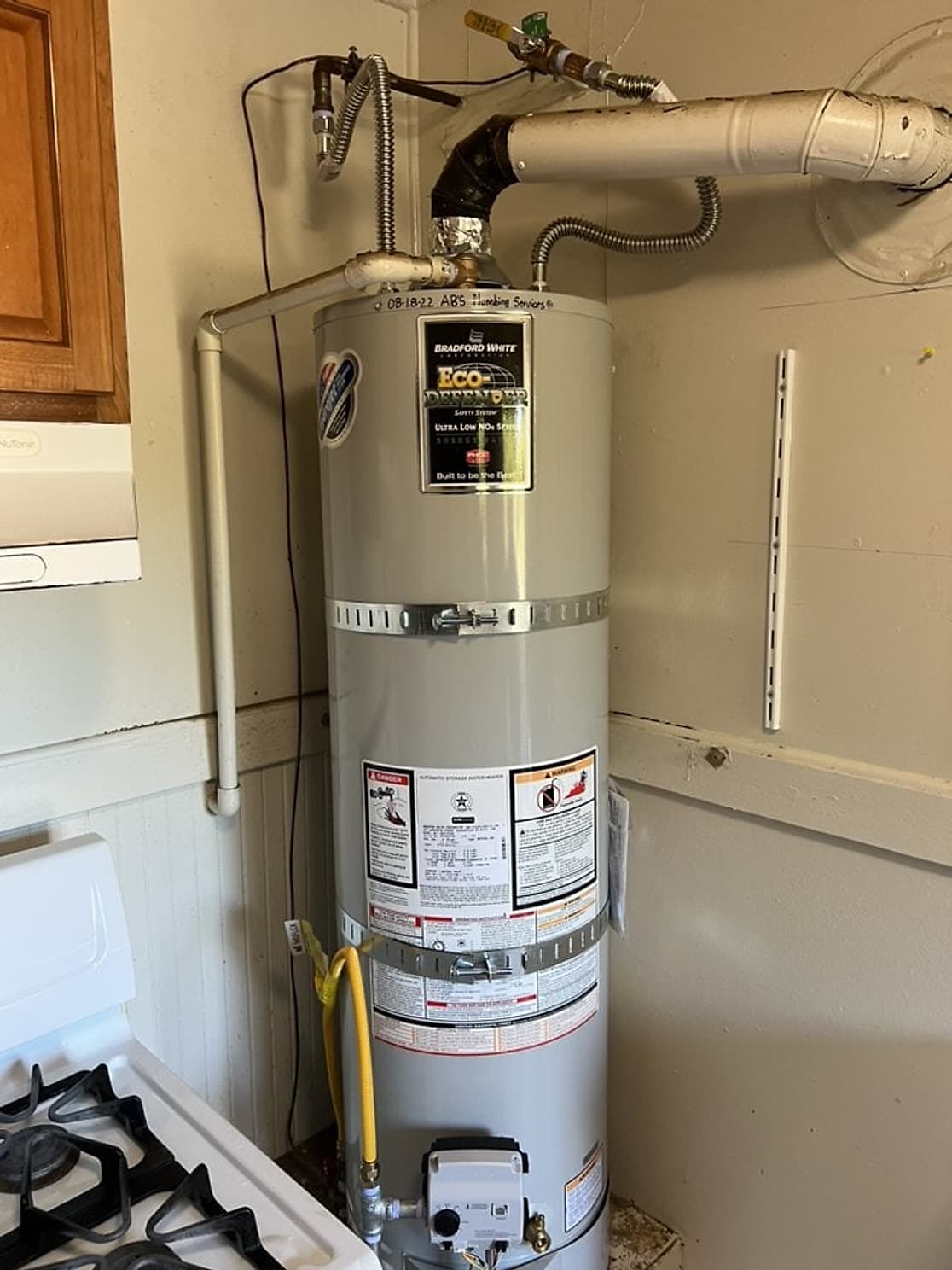 Calentador de agua de gas Bradford White nuevo con correas sísmicas, tubo de ventilación nuevo y conector de gas en un clóset de la cocina