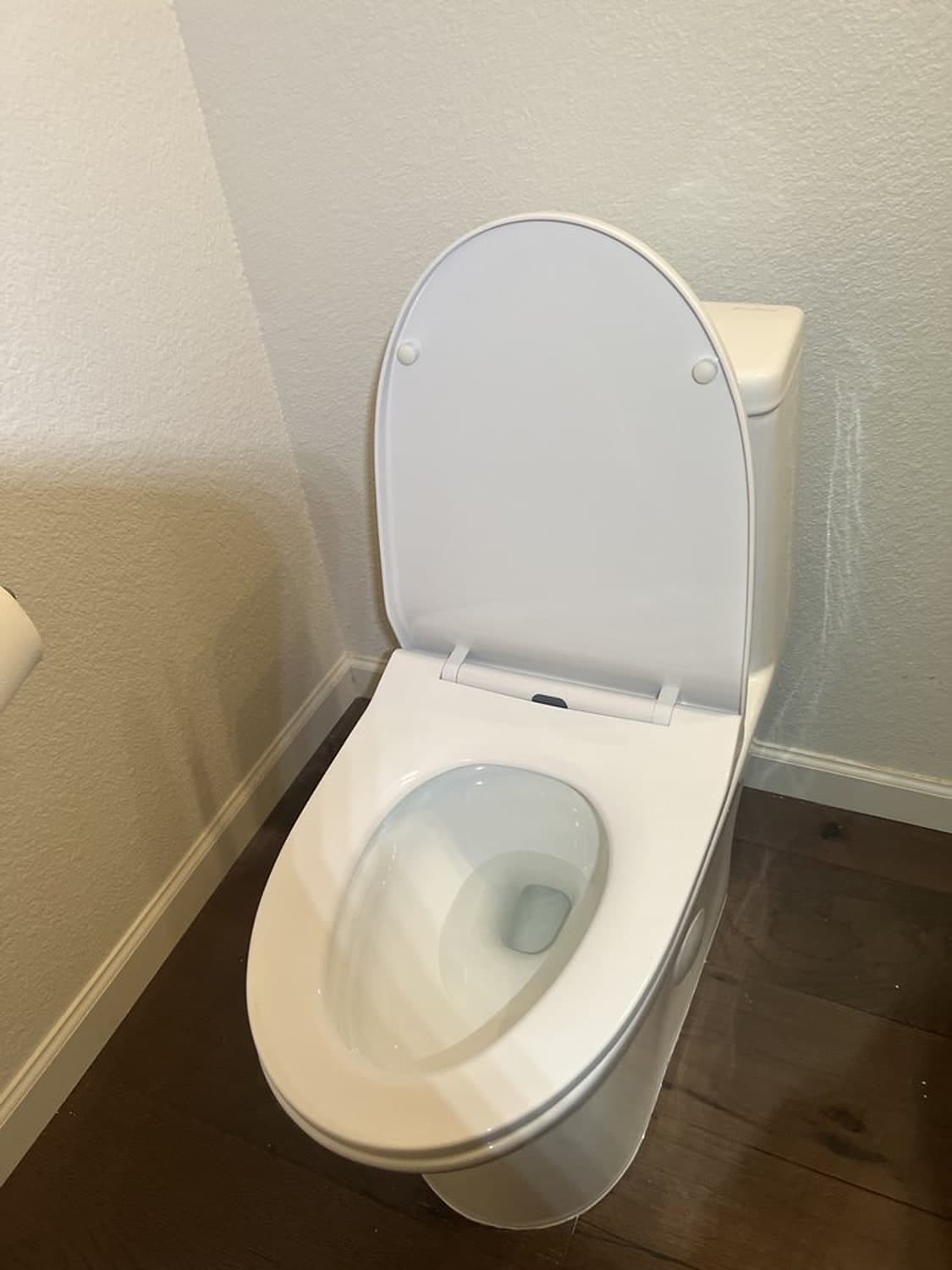 New white one-piece toilet with the lid open, installed on a wood-look floor