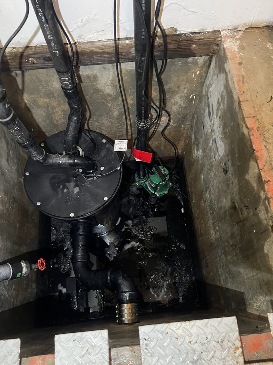 New black sewage pump and basin set in a pit, with new black discharge piping