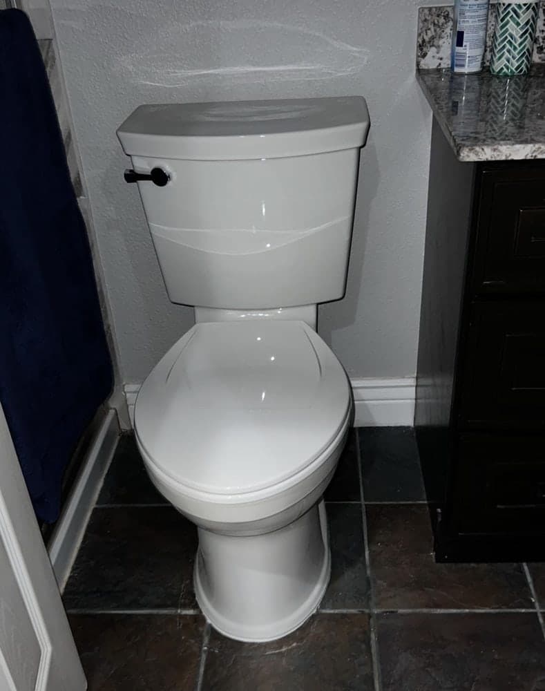 Newly installed white toilet in a bathroom with dark tile floor